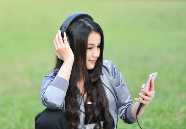 listen to music smartphones /  young woman listen to music with mobile phone outdoor happy smiling girl relax exercise listening to music with earphone in the green garden park