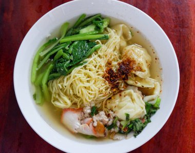 çorba şehriye Mantı kavrulmuş domuz / sarı yumurta noodle ile kırmızı kızarmış domuz eti hamur tatlısı ve Çin lahanası sebze çorba kase üzerinde ahşap masa üstten görünüm