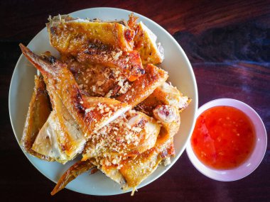 Izgara tavuk plaka üzerinde / plaka üzerinde ahşap masa ve chili sos cup doğranmış Tay tarzında ızgara tavuk kadar yakın