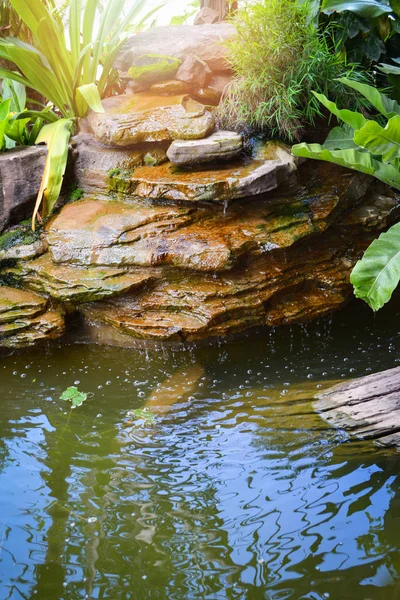 小さな池の滝デザイン石や庭の植物 — ストック写真