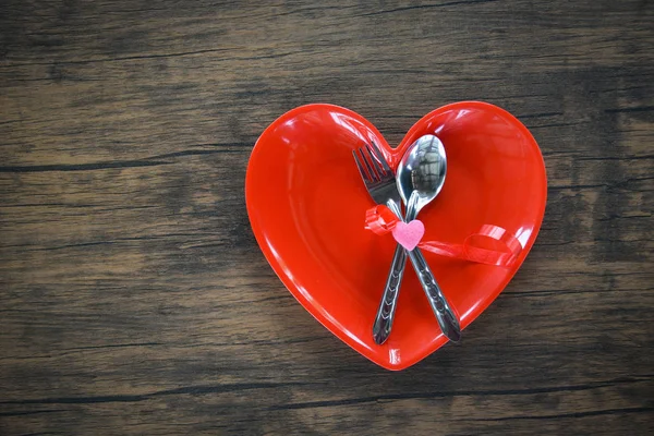 Valentines dinner romantic love food and love cooking concept - Romantic table setting decorated with fork spoon in red heart plate on wooden rustic texture background