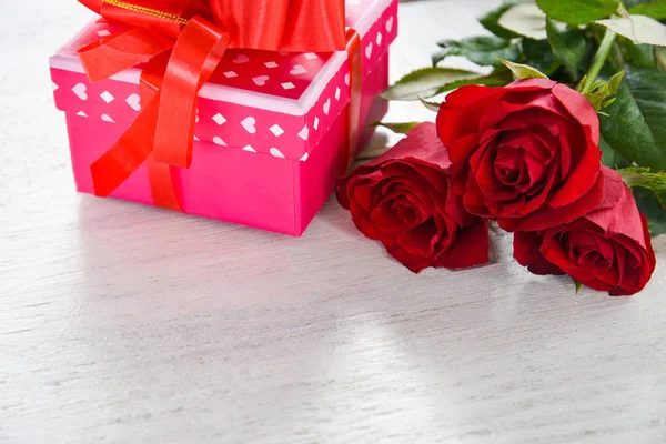 Valentines day gift box flower love concept / pink gift box with ribbon bow red roses flower on white wooden background copy space