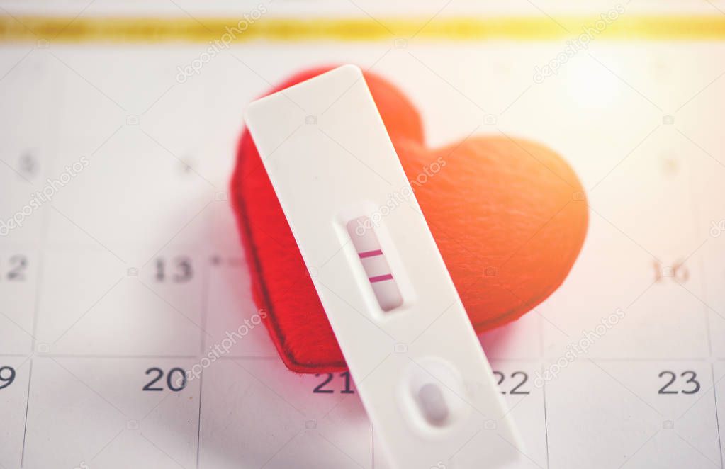 Pregnancy Tests Pregnant woman concept / positive result two lines planning a baby motherhood and healthcare and red heart on calendar background 