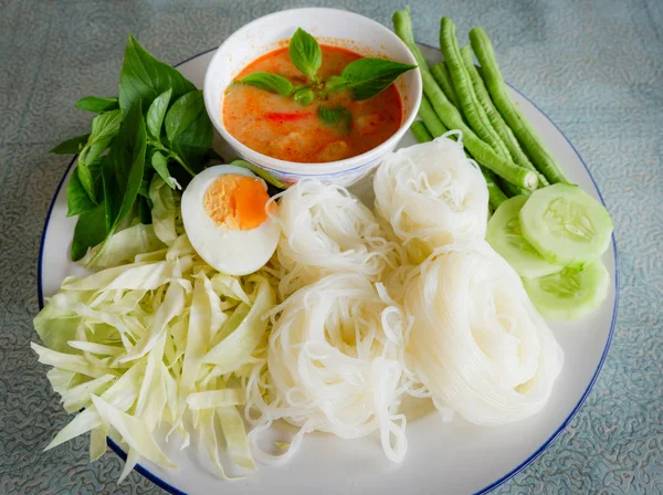 Thai rice noodle or rice vermicelli noodle and curry soup sauce on plate with vegetable yardlong , cucumber  bean and egg / Thai style food delicious