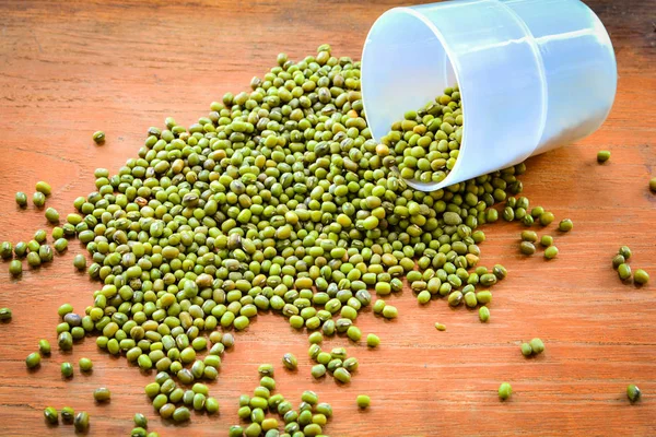 Mung beans / pile of mung beans seed with plastic cup on wood background in selective focus