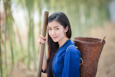 Women asia farmer in bamboo forest nature / Portrait of beautiful young asian woman happiness smile with basket for harvest agriculture in countryside village rustic - Life young girl dress tribe  clipart