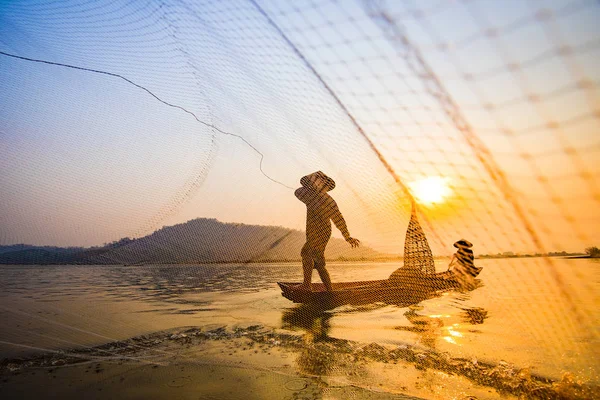 Fisherman on boat river sunset / Asia fisherman net using on wooden boat casting net sunset or sunrise in the Mekong river - Silhouette fisherman boat with mountain background life person countryside