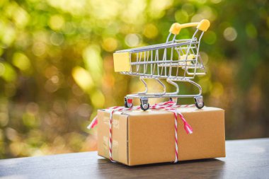 Alışveriş sepeti doğa yeşil bokeh arka plan üzerinde / karton kutu ambalaj üzerinde sarı alışveriş sepeti konseptiyle Black Friday alışveriş Online alışveriş tatil parsel kutusu - hazırlamak