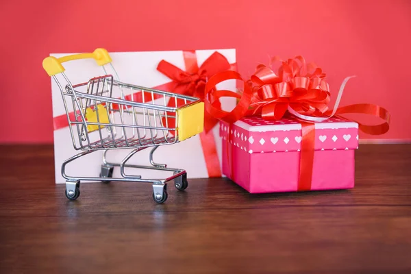 情人节购物和礼品卡礼品盒购物车 粉红礼品盒与红色丝带蝴蝶结礼品卡快乐圣诞快乐新年在红色背景 购物假期 — 图库照片