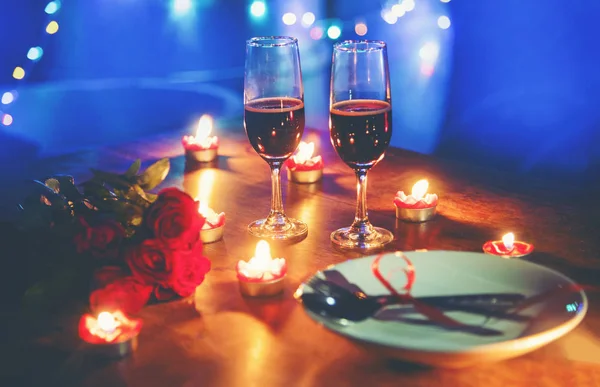 Valentines dinner romantic love concept / Romantic table setting decorated with Red heart fork spoon on plate and couple champagne glass wine roses with candlelight on wooden table dinner at night