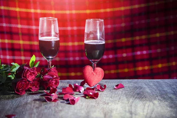 Glass of red wine on bar Valentines dinner romantic love concept / Romantic table setting decorated with couple champagne glass wine roses petals flower and heart on rustic table dinner night light