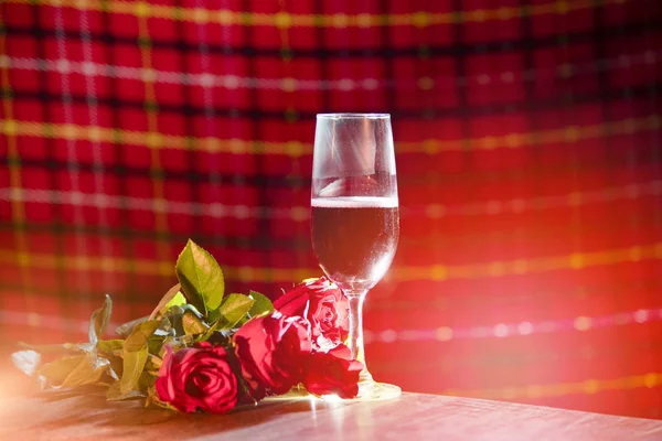 Glass of red wine on bar Valentines dinner romantic love concept / Romantic table setting decorated with champagne glass wine roses flower on rustic table dinner night light