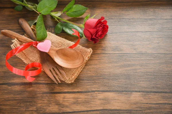 Valentines dinner romantic love food and love cooking concept - Romantic table setting decorated with wooden fork spoon roses flower on rustic wooden background