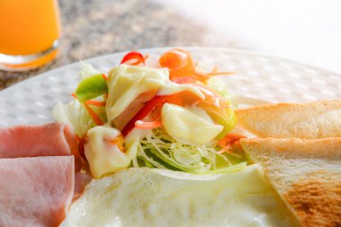 Odaya Servis Kahvaltı Sağlıklı üstten görünüm / sabah gıda İngiliz kahvaltısı tost ekmek sosis kızarmış yumurta jambon ve portakal suyu taze sebze salatası krema soslu salata yiyecek yemek masası üzerinde beyaz plaka üzerinde