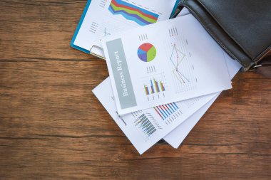 İş raporu hazırlama grafikler evrak çantası üzerinde grafik / istatistik Özet raporda pasta grafik kağıt iş belge mali grafik üzerinde daire ve ahşap masa arka plan üzerinde grafik