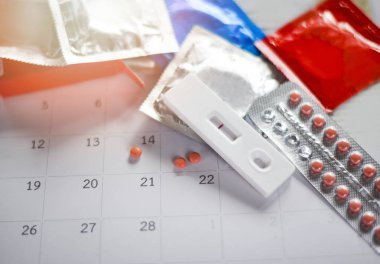 Doğum kontrol hapı ve gebelik testleri önlemek hamilelik Doğum kontrolü kavramı / prezervatif üzerinde takvim arka plan - Sağlık ve tıp ile Doğum kontrolü