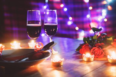 Sevgililer akşam yemeği romantik aşk kavramı / gece yemekte ahşap masa üzerinde kırmızı kalp çatal kaşık plaka ve çift şampanya cam şarap gül mum ışığı ile romantik tablo ayarını süslenmiş