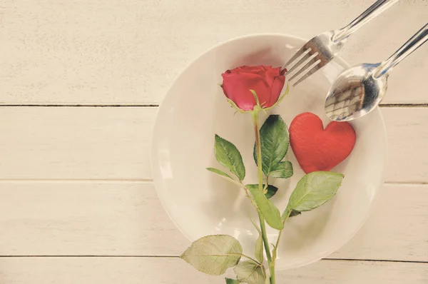 Valentines dinner romantic love food and love cooking concept - Romantic table setting decorated with fork spoon red heart and roses on plate on table background top view copy space tone vintage
