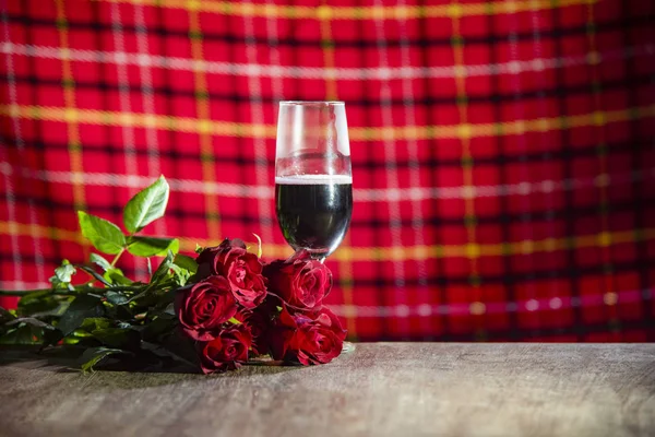 Glass of red wine on bar Valentines dinner romantic love concept / Romantic table setting decorated with champagne glass wine roses flower on rustic table dinner night light