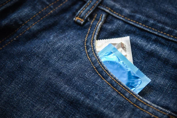 Condoms package in jeans / Colorful of Condom in pocket blue jeans on background - Prevent Pregnancy or sexually transmitted disease concept