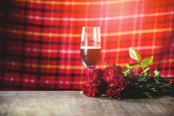 Glass of red wine on bar Valentines dinner romantic love concept / Romantic table setting decorated with champagne glass wine roses flower on rustic table dinner night light