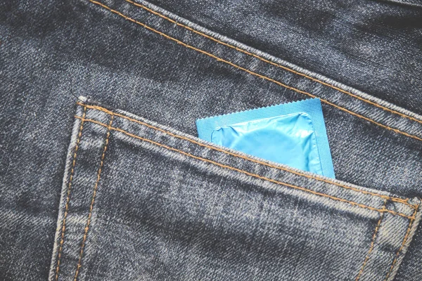 Condoms package in jeans / Colorful of Condom in pocket blue jeans on background - Prevent Pregnancy or sexually transmitted disease concept