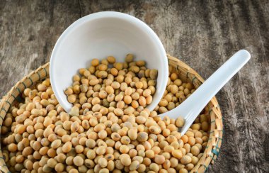 soya fasulyesi ya da soya fasulyesi tohumu bambu sepet beyaz Kupası ve rustik ahşap zemin üzerine kaşık tahıl