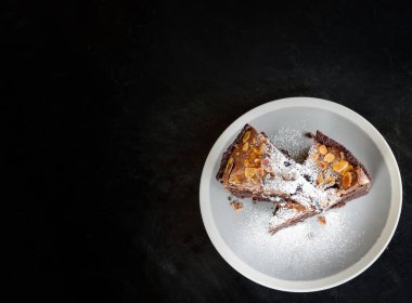 Kek Kek tablo / parça çikolatalı kek kakao ile fındık ve şeker üstten görünüm kek üzerine krema dilim beyaz plaka üzerinde ahşap koyu arka plan 