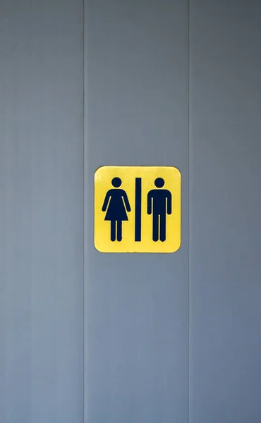 灰色のドア壁に男性と女性のトイレ記号黄色背景 — ストック写真