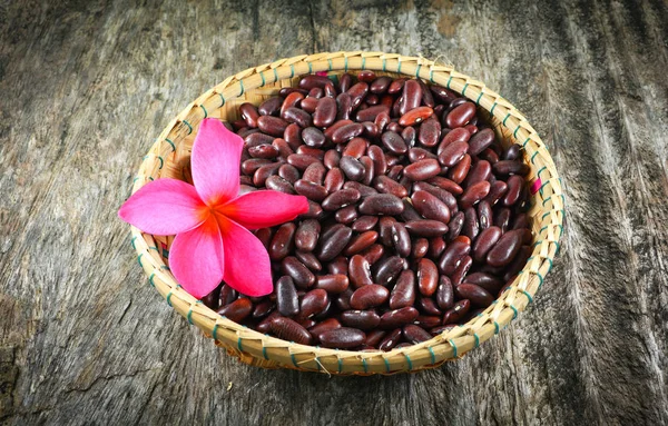 Red beans azuki or red kidney bean grain seed on basket and pink flower on rustic wood background