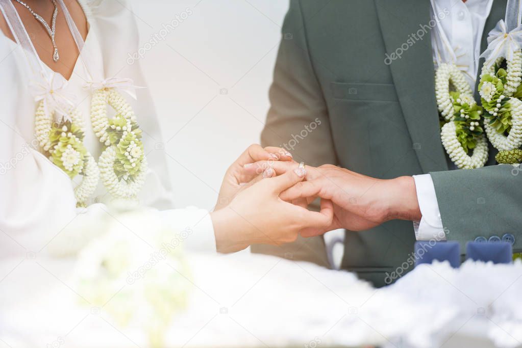 The bride wears a wedding ring on the groom on left hand ring finger on her wedding day