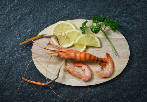 在深色背景上 用草药和香料在切菜板上煮熟的贝类海鲜虾虾 — 图库照片