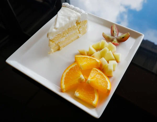 Fatia de frutas e bolo de leite no prato branco — Fotografia de Stock