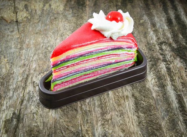 Torta arcobaleno colorato con panna e ciliegia rossa sul vecchio woo — Foto Stock