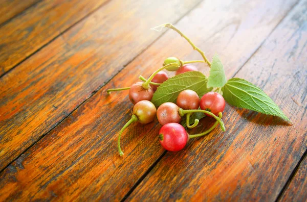 Fruta y hoja de cereza jamaicana sobre fondo de madera — Foto de Stock