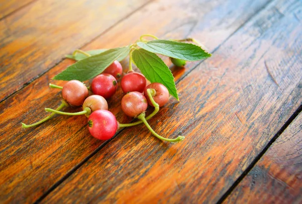 Fruta y hoja de cereza jamaicana sobre fondo de madera — Foto de Stock