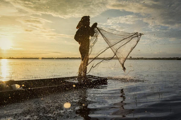 Asia fisherman using net fishing on wooden boat casting net suns