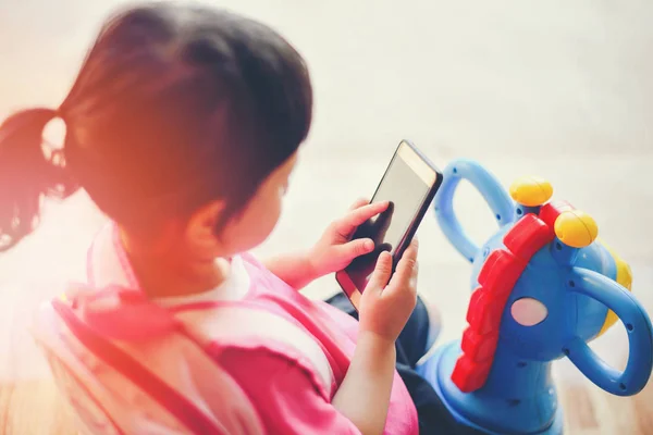 Meisje houdt de telefoon in de hand en spelen smartphone kijken naar winkelwagen — Stockfoto