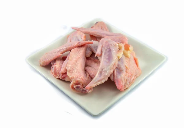 Свежие сырые куриные крылышки на тарелке на белом фоне — стоковое фото