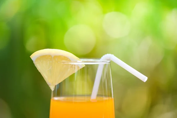 Jus d'orange avec morceau de fruit orange sur verre vert nature — Photo