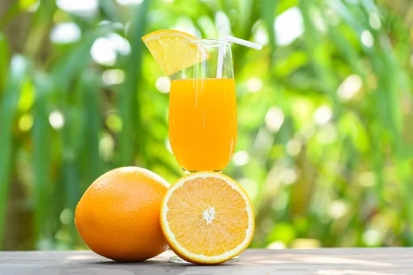 Jus d'orange avec morceau de fruit orange sur verre vert nature — Photo