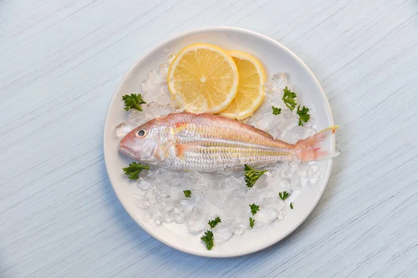 Свежая рыба на льду с лимоном и петрушкой на белом столе ba — стоковое фото