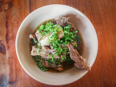 Ahşap masa arka planda sebze ile kase kemik çorbası/Bo