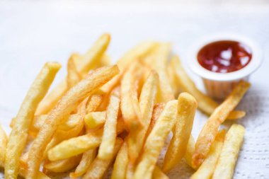 Yemek masasında ketçap ile beyaz kağıt üzerinde patates kızartması 