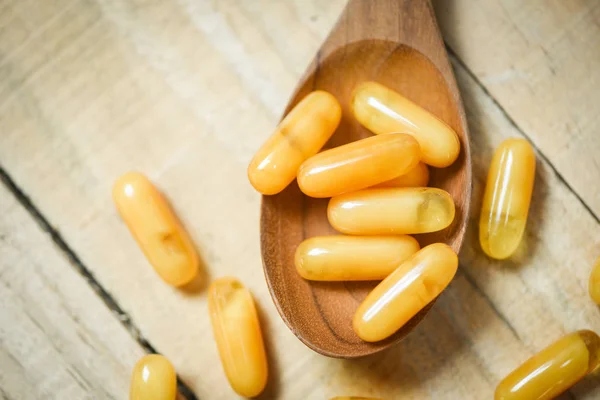 Royal jelly capsules in wooden spoon and wood table background / — Stock Photo, Image