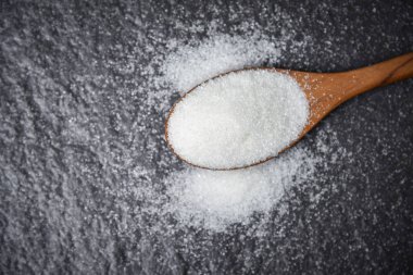Tahta kaşıkta beyaz şeker ve koyu arkaplan 