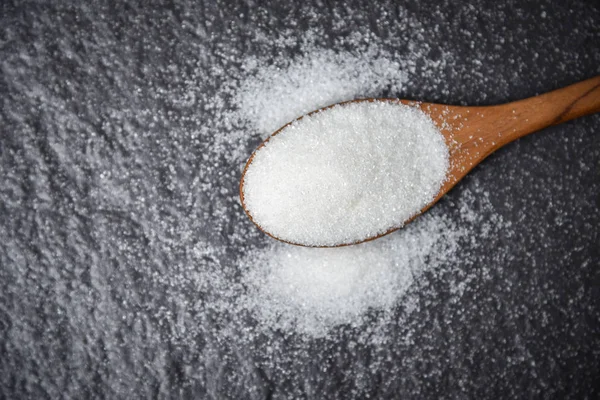 White sugar on wooden spoon and dark background — 스톡 사진