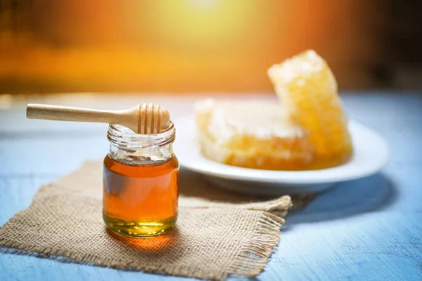 Honey in jar with wooden dipper and honeycomb on white plate nat — Stock Photo, Image