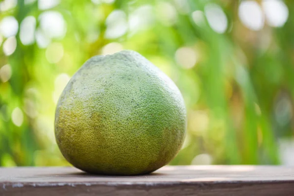 Verse pomelo fruit op houten tafel en groene natuur achtergrond — Stockfoto