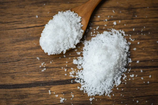 Salz in Holzlöffel und Haufen von weißem Salz auf Holz Hintergrund — Stockfoto
